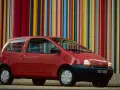 Renault Twingo 1 rouge devant un mur de bandes colorées verticales.