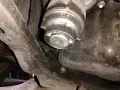 Filtre à huile de voiture sous le véhicule, avec une clé carrée insérée.