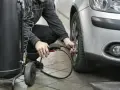 Un homme gonfle un pneu de voiture avec un manomètre et un compresseur.