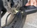 Gonfleur de pneu sans fil connecté à la valve d'une roue de moto, affichant la pression.