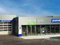 Façade d'un centre auto Point S avec des portes de garage et des panneaux indiquant les services (vidange, freins, pneumatiques, pare-brise).