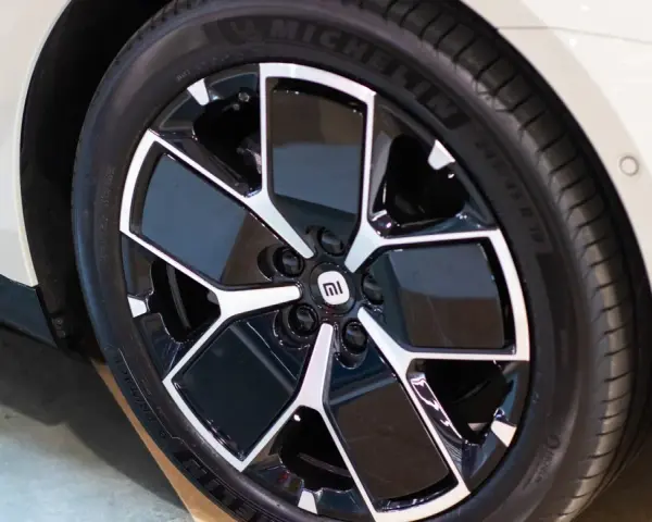 Pneu Michelin sur jante noire et argentée avec logo Mi sur une voiture blanche.